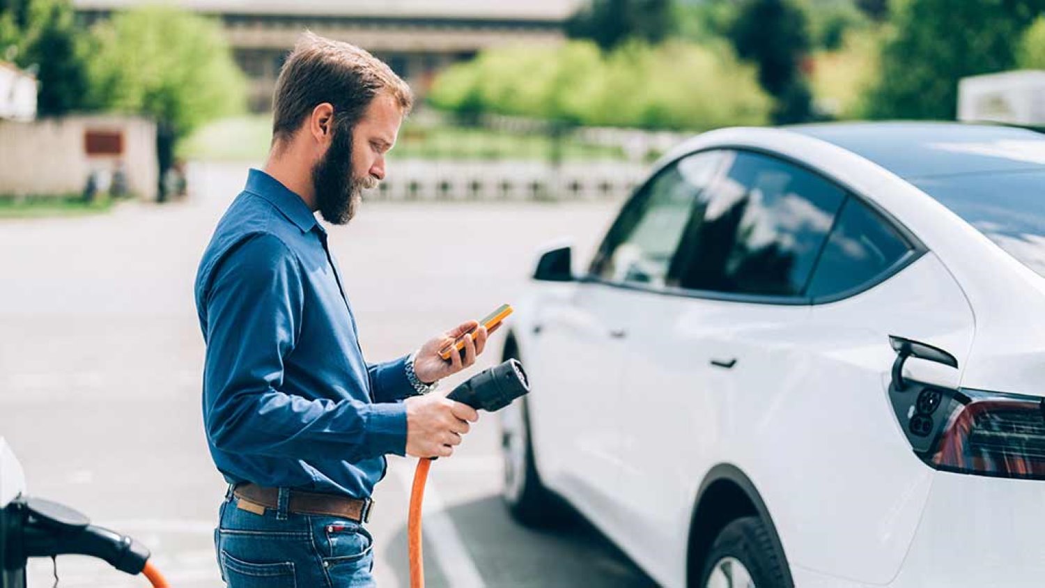 Mies laittaa sähköautoa lataukseen