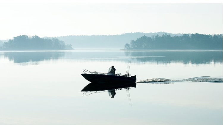 Kalastusvene lipuu tyynellä merellä saaristossa