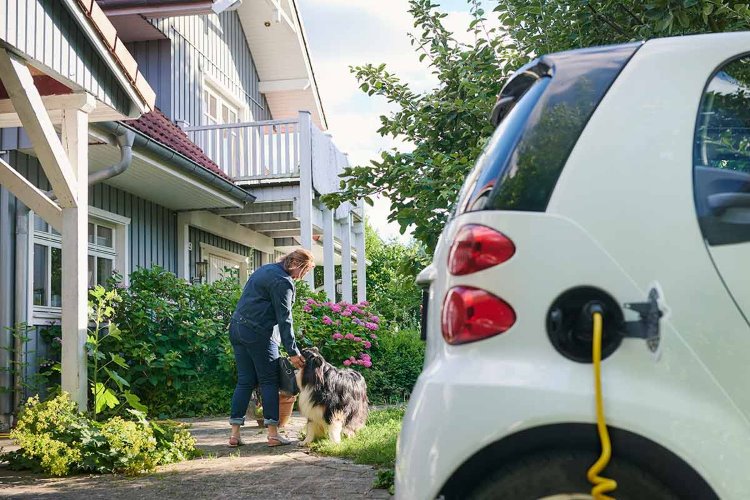 Sähköauto on latauksessa omakotitalon pihalla