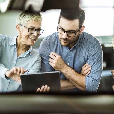 Perhe valitsee autoa autokaupassa myyjän kanssa